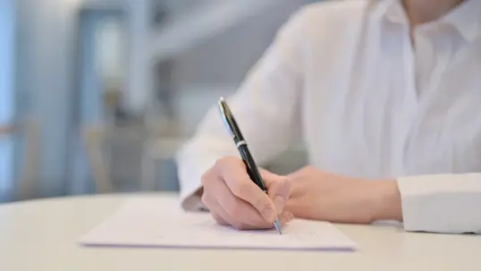 Woman Writing on Paper in Cafe, Close up