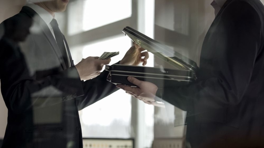 Man looking at money in briefcase